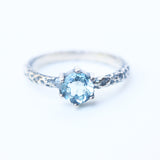Round faceted Swiss blue topaz ring in silver bezel and prongs setting on sterling silver oxidized hard texture band