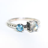 Faceted moonstone ring in silver bezel setting and blue topaz on the side with sterling silver band - Metal Studio Jewelry