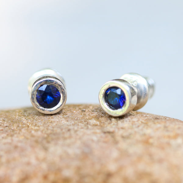 Sterling silver stud earrings with faceted blue sapphire in bezel setting with sterling silver post and backing - Metal Studio Jewelry