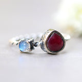 Teardrop faceted red ruby ring in silver bezel setting and tiny round moonstone with sterling silver twist design band