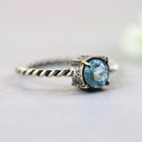Round faceted blue topaz ring in silver bezel and brass prongs setting with sterling silver twist design band - Metal Studio Jewelry