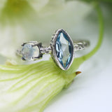 Marquis faceted blue topaz ring in silver bezel setting and round moonstone on the side with sterling silver hard texture band - Metal Studio Jewelry