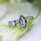 Marquis faceted blue topaz ring in silver bezel setting and round moonstone on the side with sterling silver hard texture band - Metal Studio Jewelry