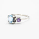 Oval faceted blue topaz ring in silver bezel and prongs setting and tiny amethyst on the side with sterling silver hammer texture band - Metal Studio Jewelry