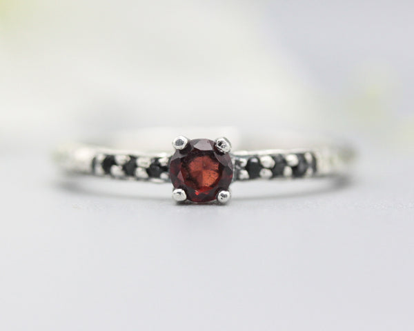 Garnet round faceted ring in prongs setting with tiny black spinel on sterling silver oxidized hammer texture band