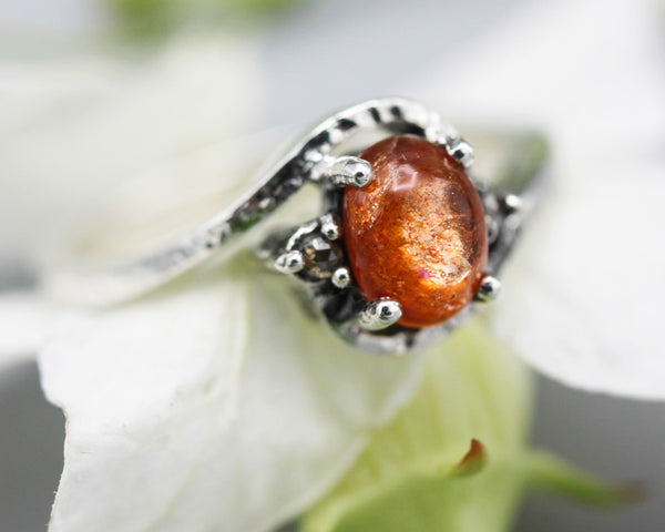 Cabochon sunstone ring with tiny champagne diamonds side set gems in prongs setting with sterling silver texture band - Metal Studio Jewelry