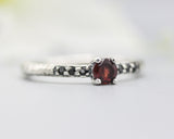 Garnet round faceted ring in prongs setting with tiny black spinel on sterling silver oxidized hammer texture band