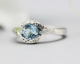 Bypass style ring sterling silver hammer texture with round faceted blue topaz at the center
