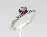Oval faceted garnet ring in prongs setting with tiny black spinel on sterling silver oxidized hammer texture band