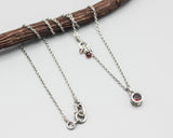 Round faceted red garnet pendant necklace in silver bezel setting with sterling silver chain