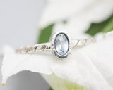Tiny oval faceted blue topaz ring in silver bezel setting on sterling silver twist design band