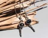 Oval Star Diopside Earrings, featuring a silver bezel setting and silver sticks and hooks on the top