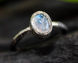Oval cabochon moonstone ring in sterling silver bezel setting with oxidized textured silver band