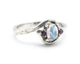 Oval cabochon moonstone ring with tiny ruby side set gems in prongs setting with sterling silver oxidized texture band