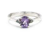 Oval faceted amethyst ring with tiny labradorite side set gems in prongs setting with sterling silver texture oxidized band