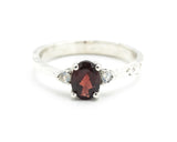Oval faceted Garnet ring with tiny moonstone side set gems in prongs setting with sterling silver texture oxidized band