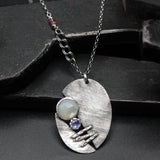 Sterling silver oval shape pendant necklace with white moonstone and tanzanite gemstone in bezel setting on sterling silver chain